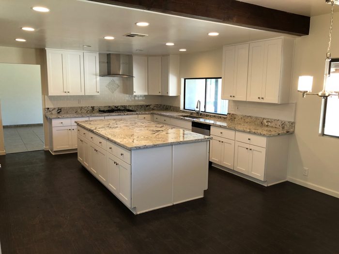 Finished kitchen remodel in Bakersfield with white shaker cabinets and a granite island