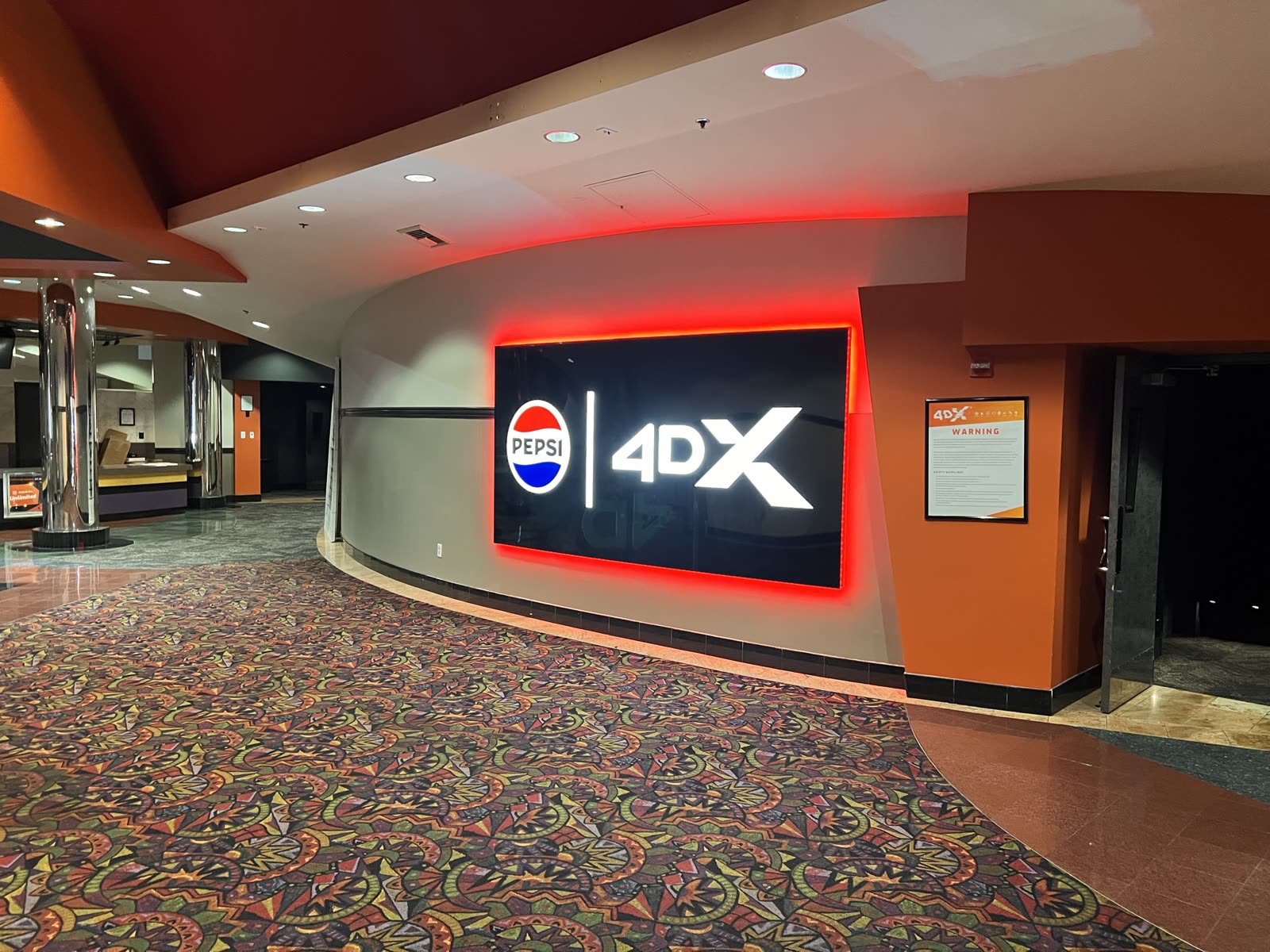 Finished cinema lobby with an illuminated 4DX auditorium entry sign and patterned carpet