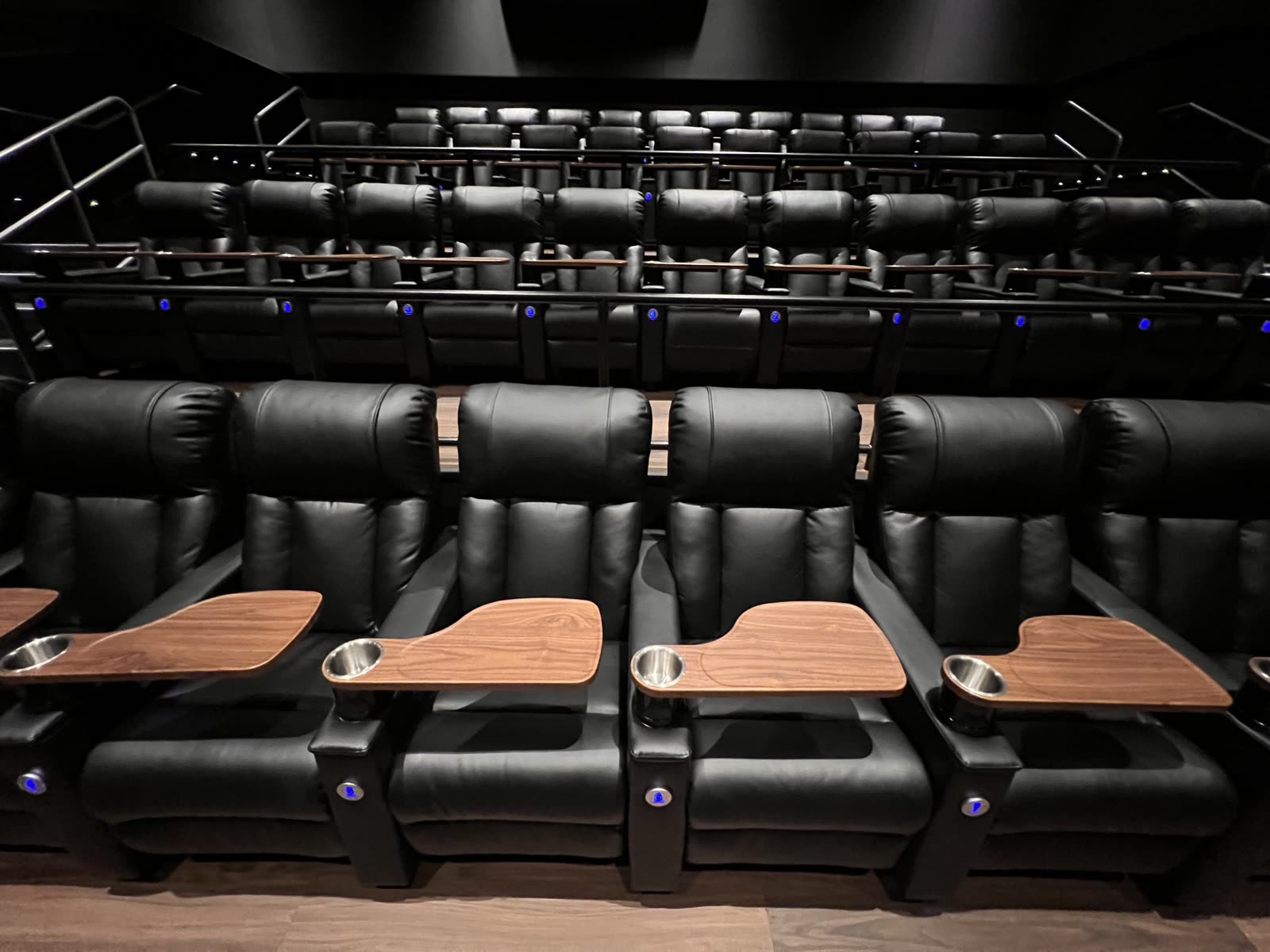 Detail of the cinema recliners with timber tray tables, cup holders and illuminated row numbers
