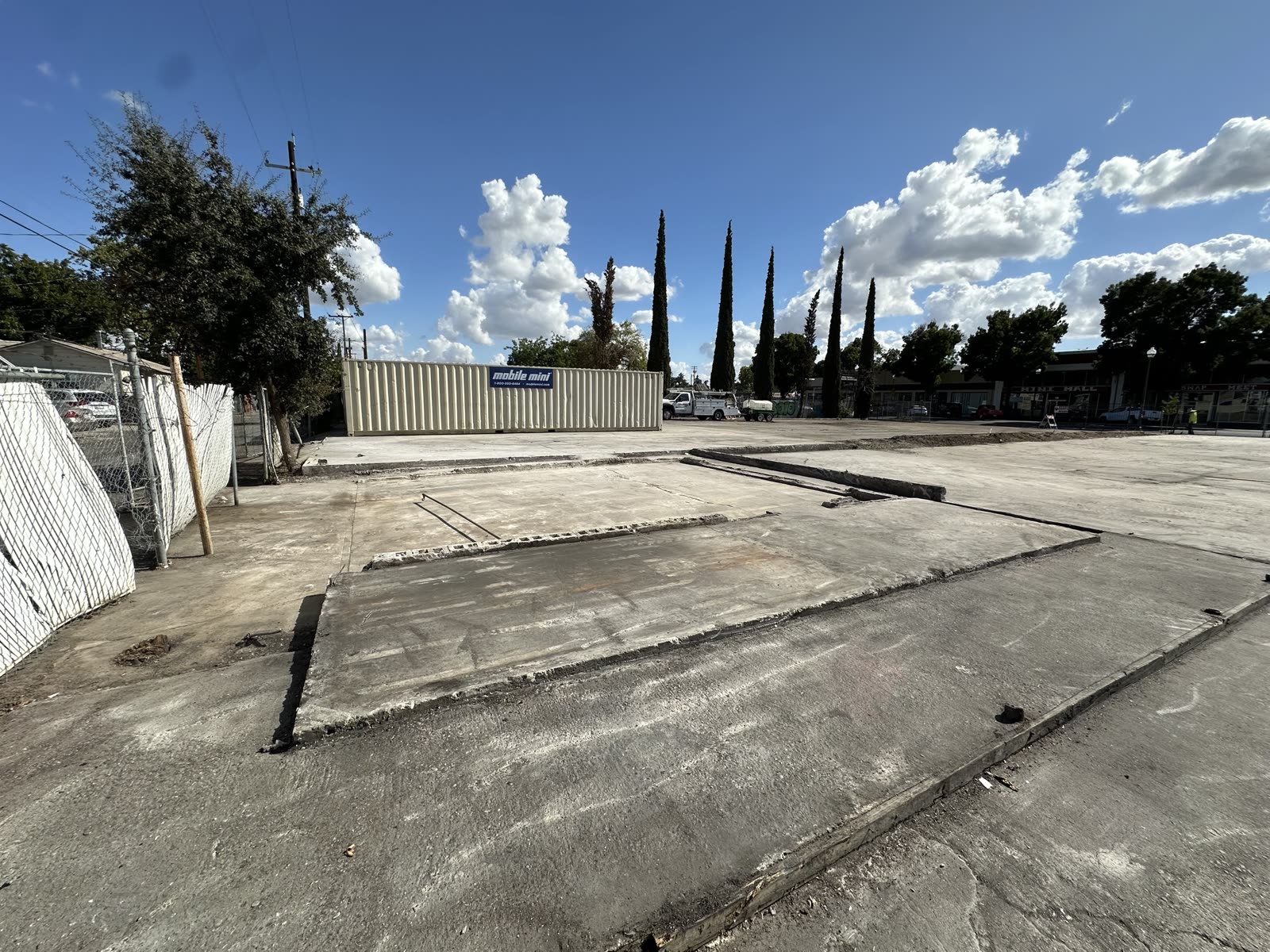 Cleared commercial slab with a storage container set along the boundary and the footprint of the old building visible