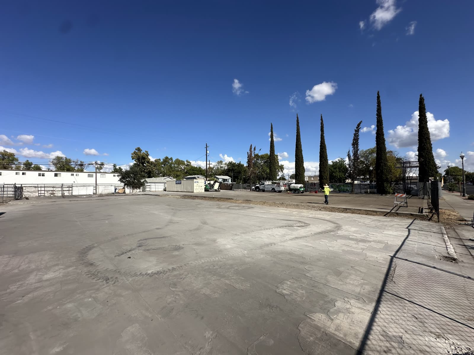Wide view of the cleared commercial lot with the slab intact and the site fence still up