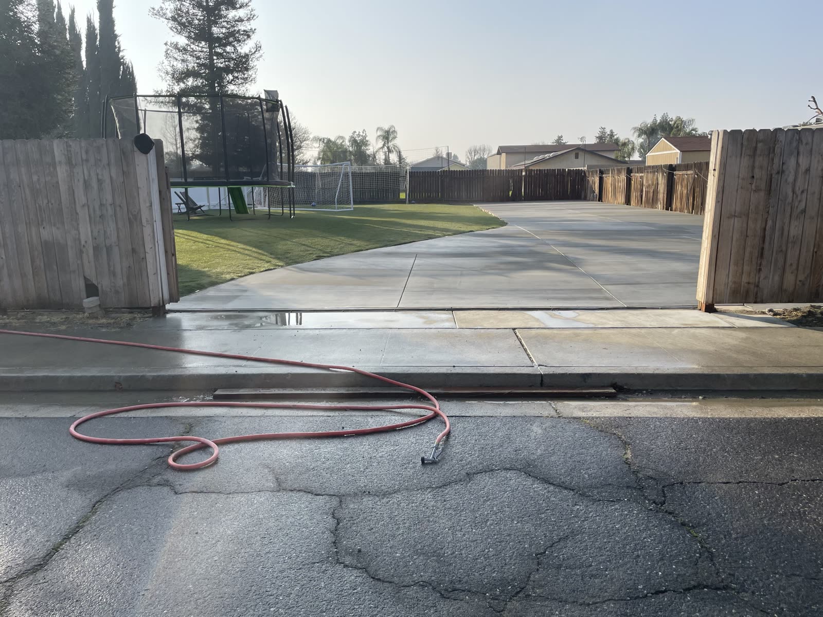 New concrete drive apron meeting the street at the gate, joints cut and finished