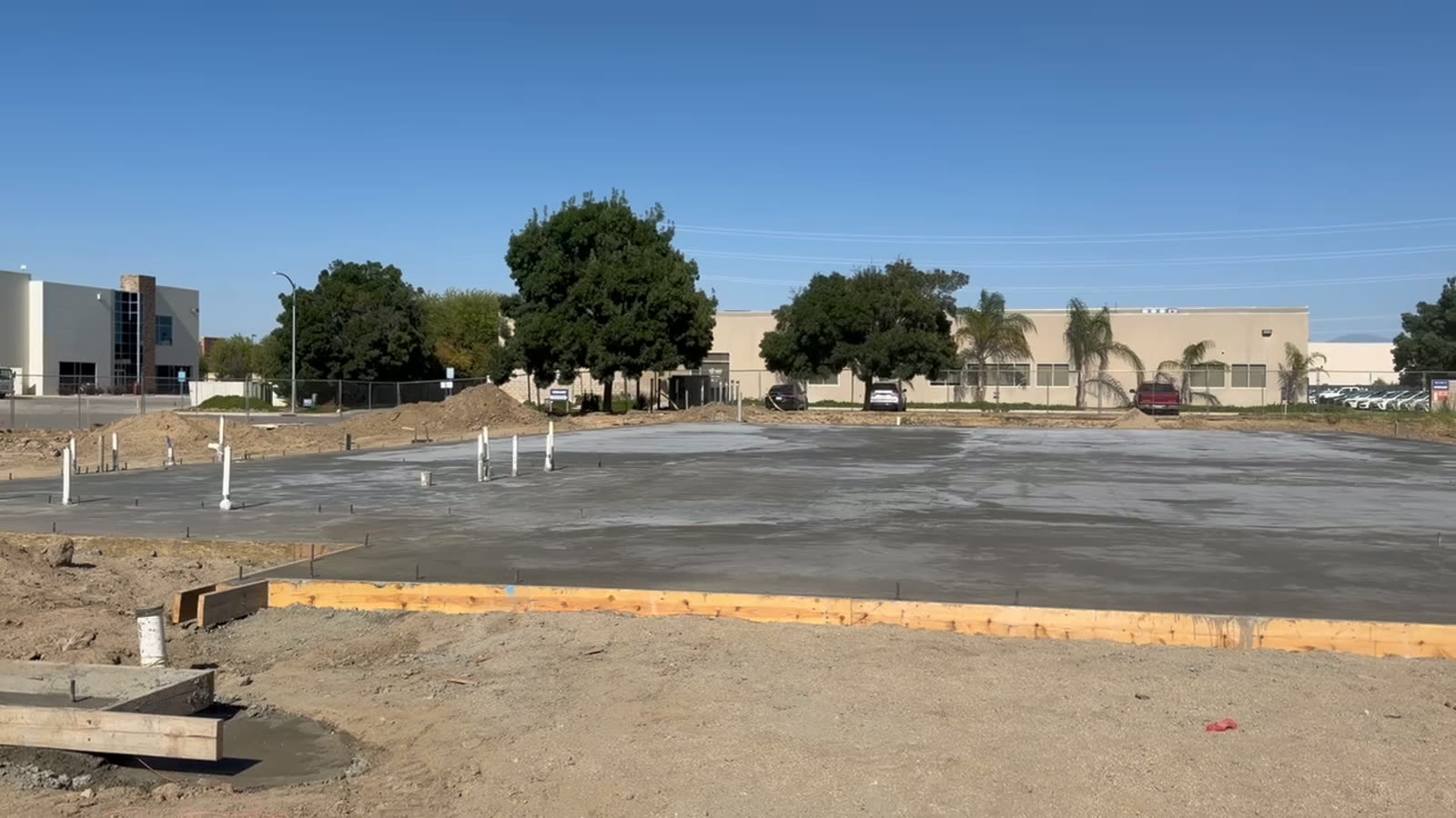 Fresh concrete paving between timber forms and new curbing on a commercial lot