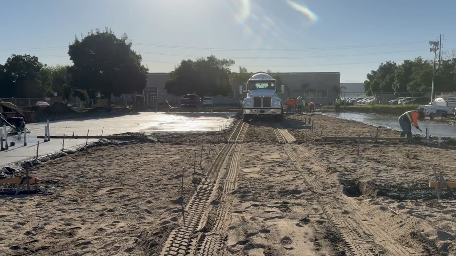 Machine working a large concrete pour on a commercial site with the building beyond