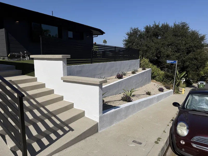 New stucco retaining walls with cast concrete caps, poured entry steps and a gravel planter bed with drought-tolerant planting