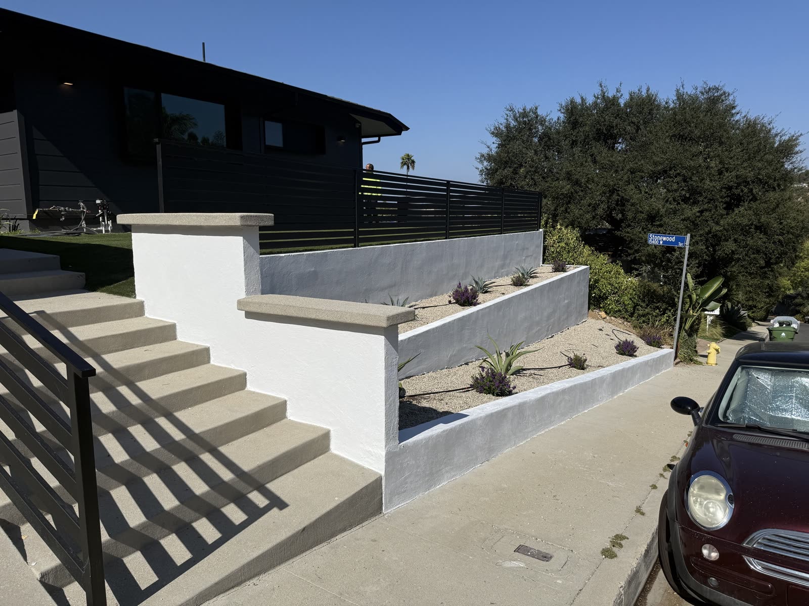 New stucco retaining walls with cast concrete caps, poured entry steps and a gravel planter bed with drought-tolerant planting