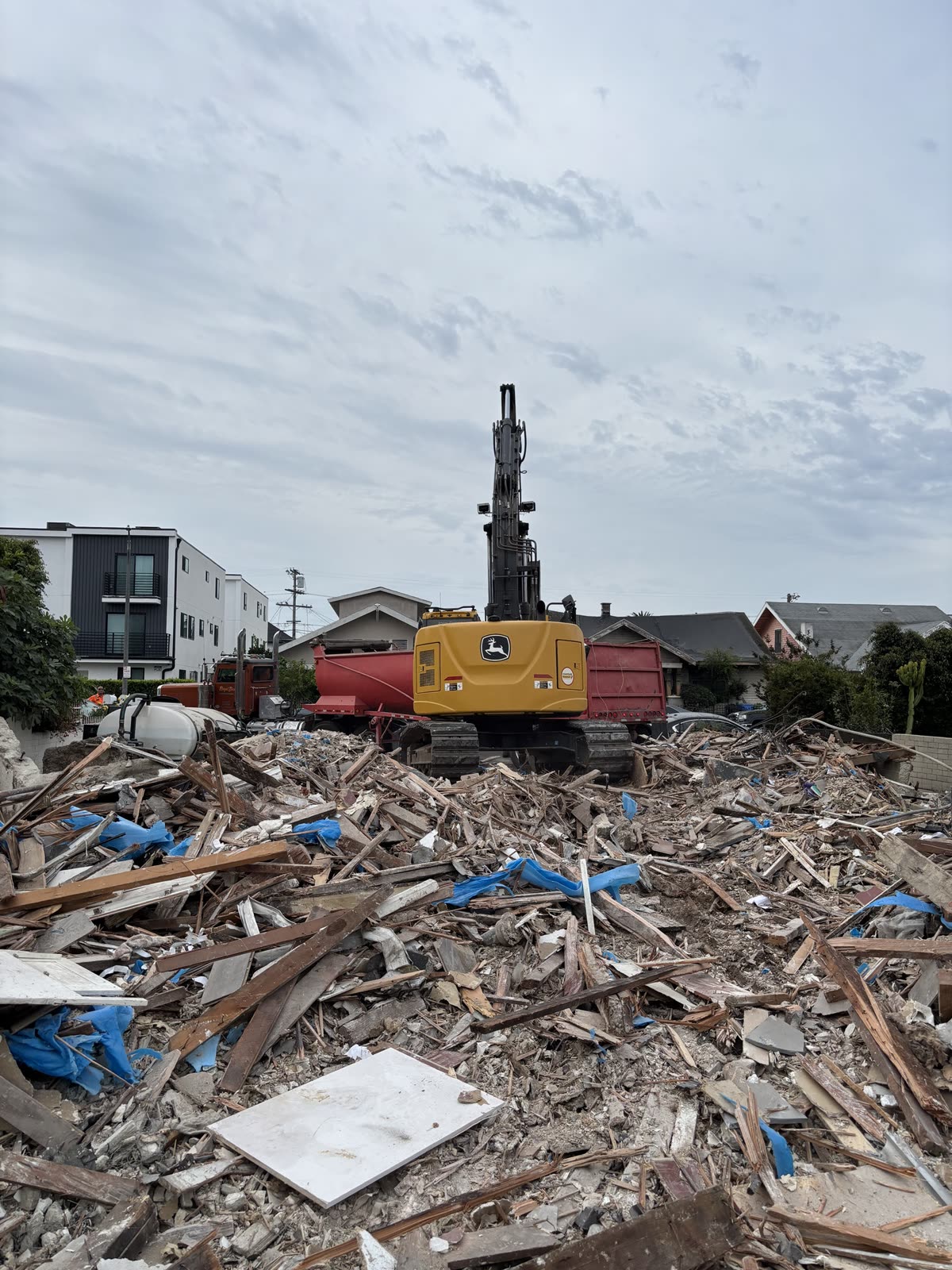 Excavator feeding mobile home debris into a roll-off bin from the stripped pad