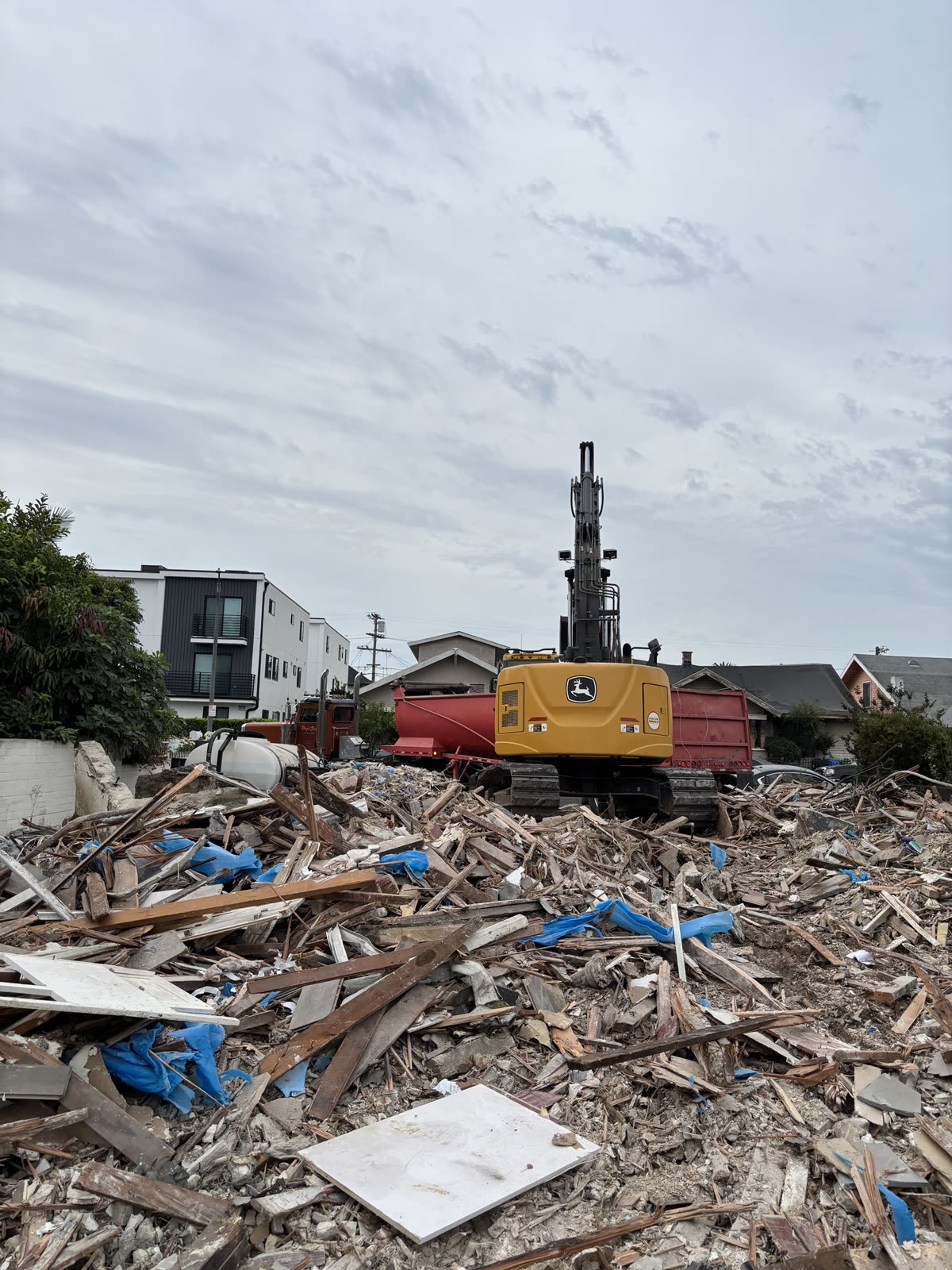 Mobile home broken down into a sorted debris pile of timber and panel, staged beside the bin