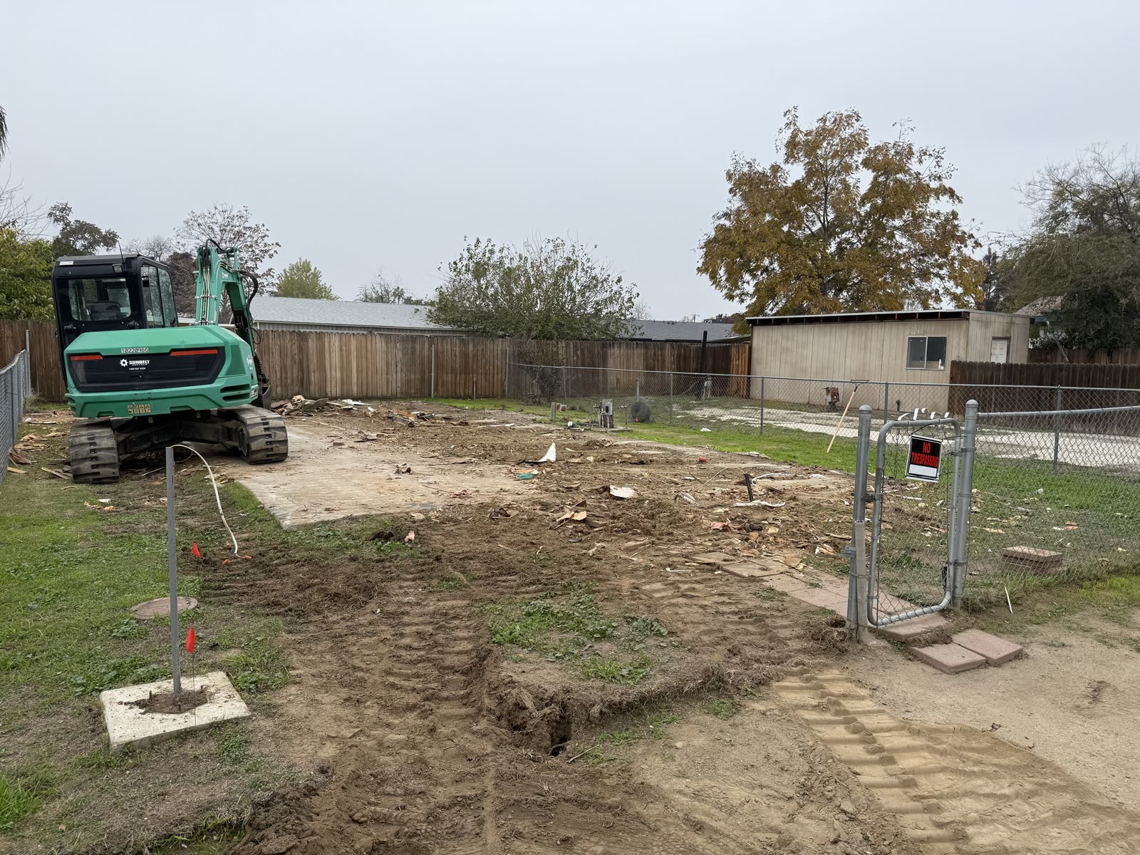 Back-yard pad cleared down to the original concrete after a mobile home removal, utilities capped and flagged