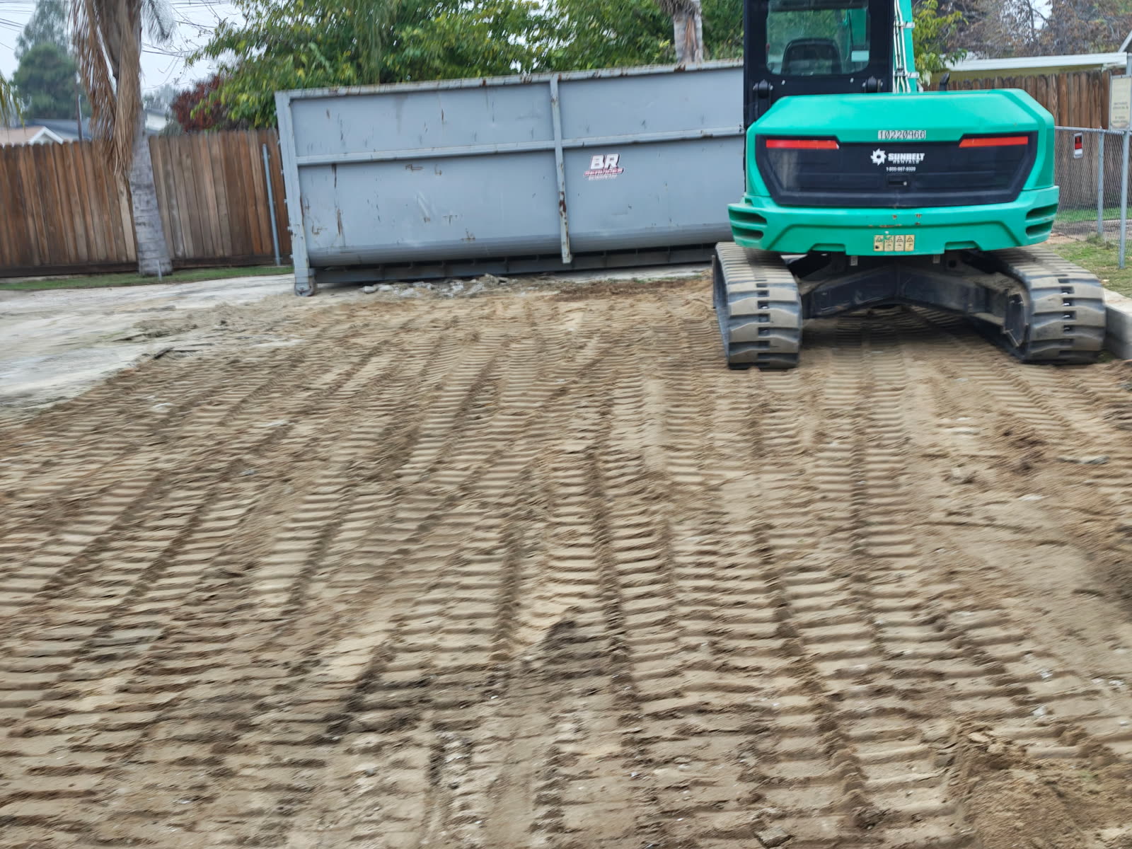Excavator tracking out a graded pad beside the bin once the structure and debris were gone