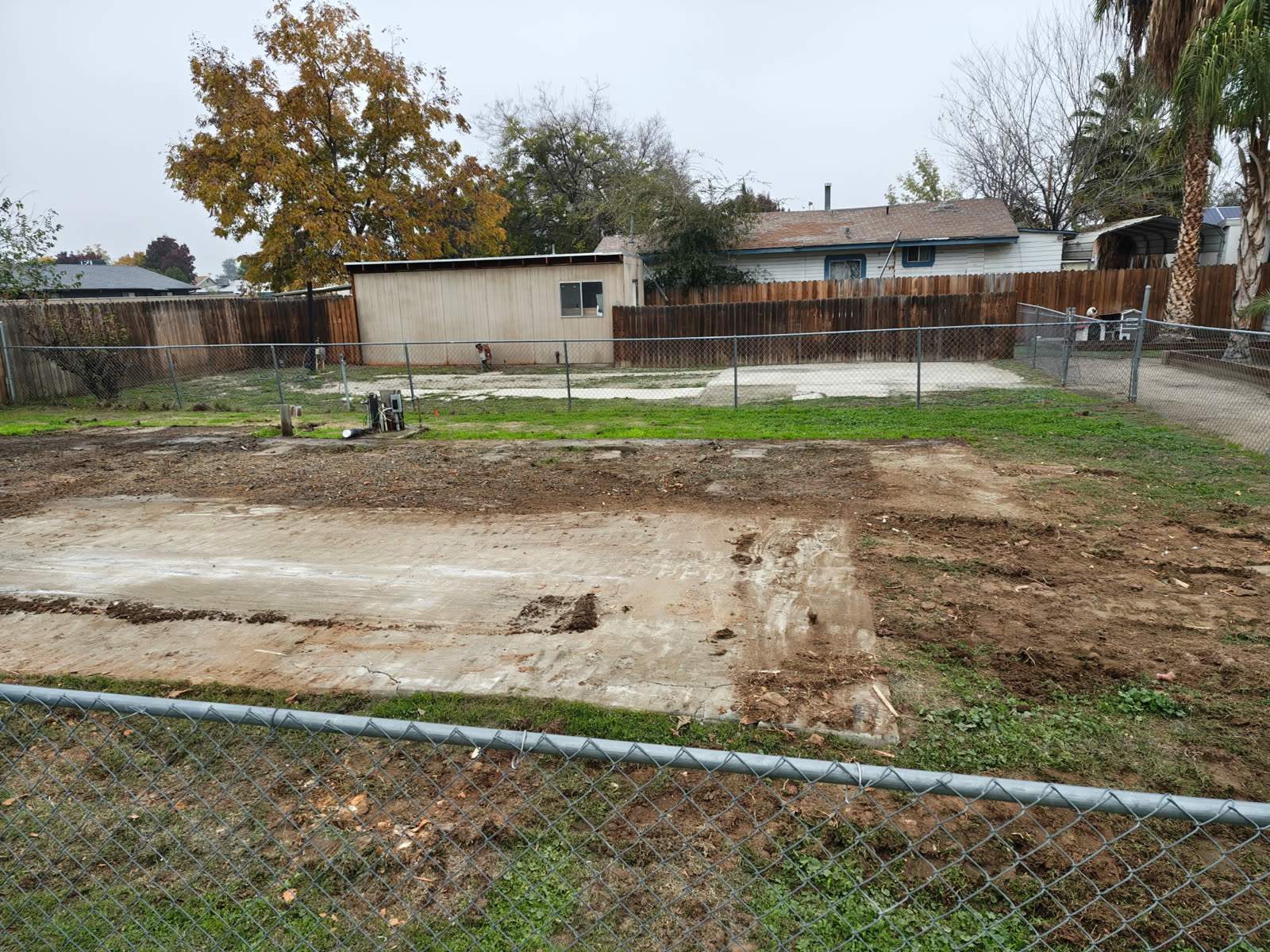 Back yard left graded and clear after a mobile home removal, with the slab swept and the lawn edge intact