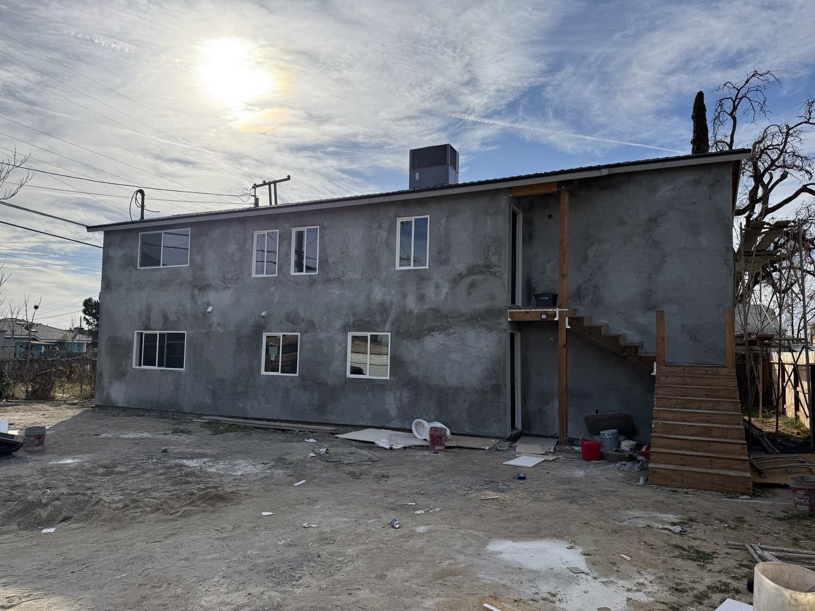 Rear of the apartment building with the brown coat complete, new windows trimmed and a packaged rooftop unit set