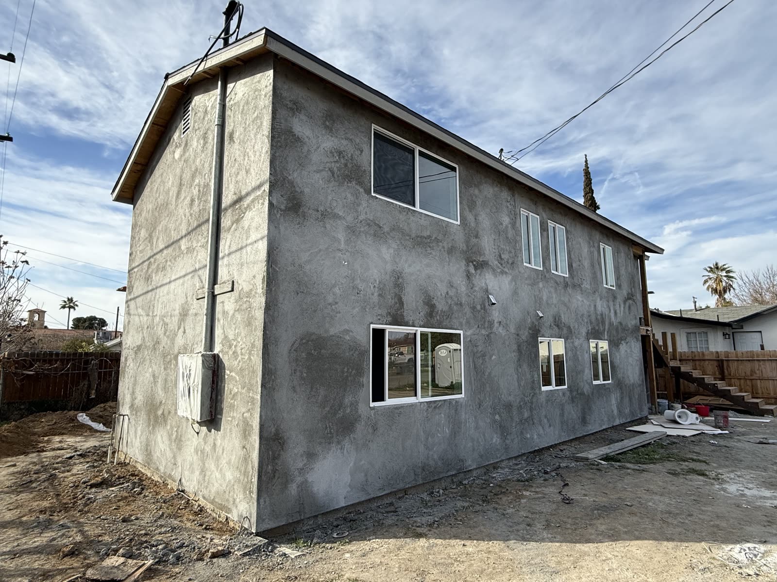 Side elevation of the apartment building rendered in gray brown-coat stucco before the finish coat