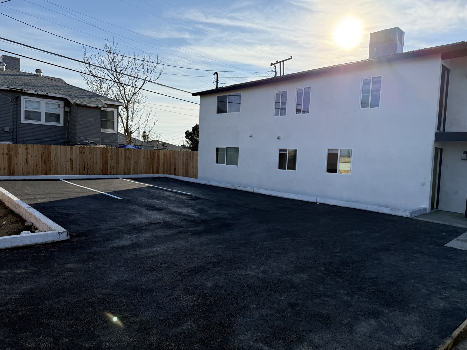 New asphalt parking lot and concrete curb running the length of the finished apartment building