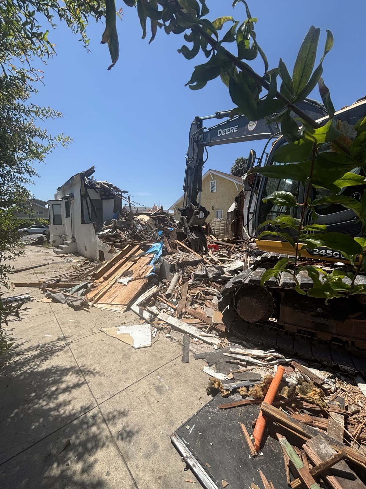 House part way down with the excavator arm in the structure and the debris dropping into the work area