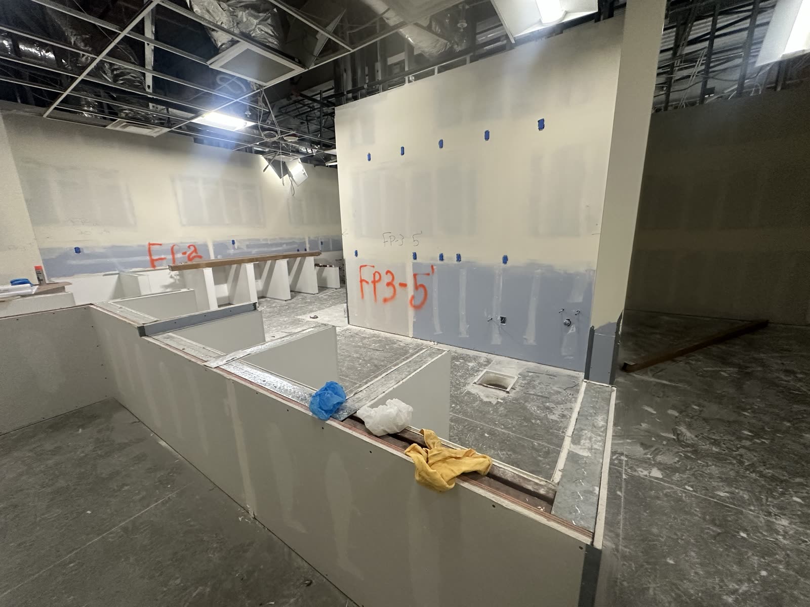 Boarded counter bulkheads and service openings formed in a commercial fit-out before finishes