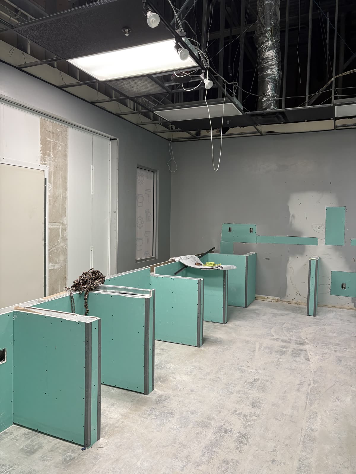 Green moisture-resistant board hung on new partitions in a commercial space, joints ready for tape