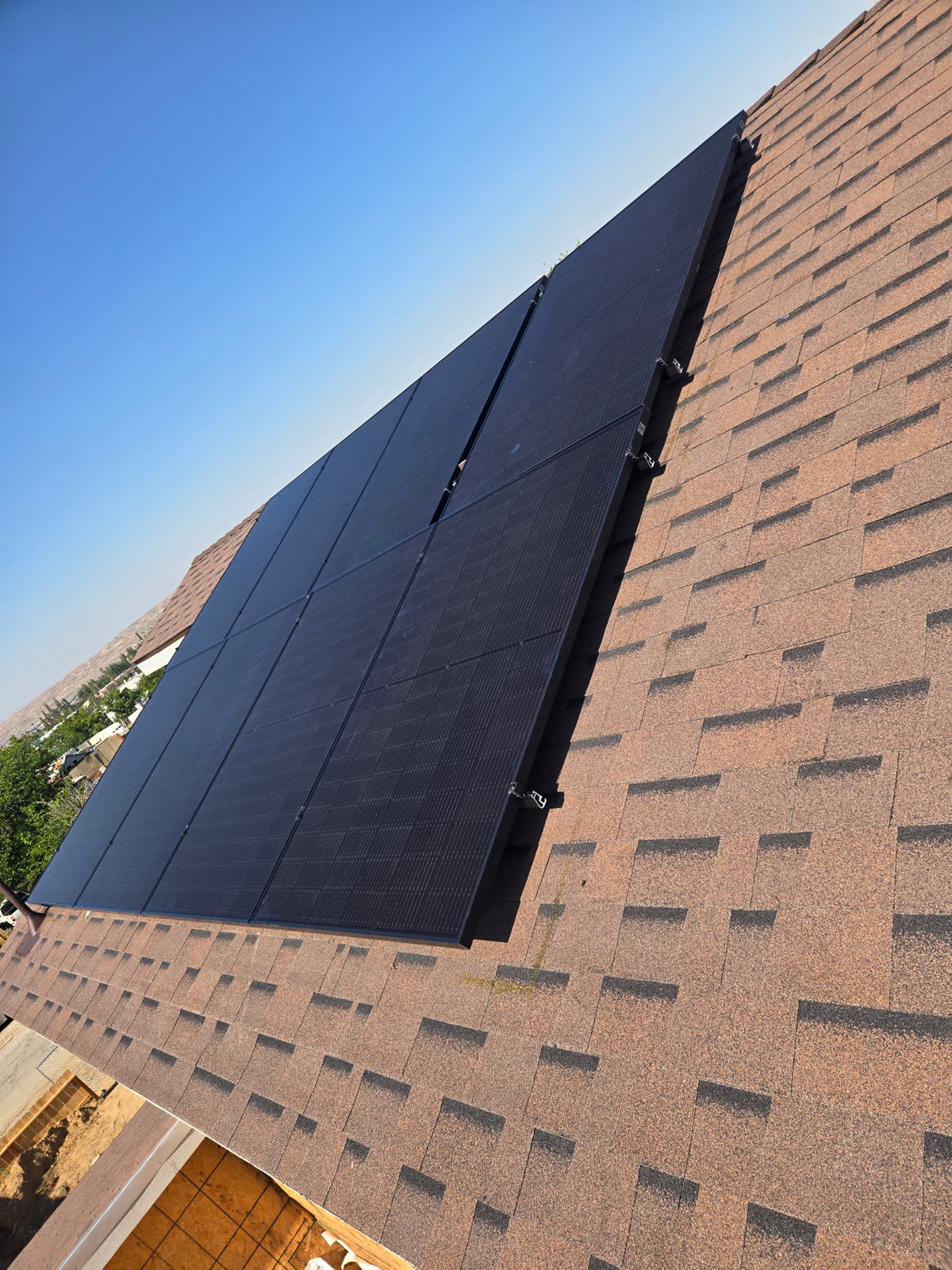 Close view of an installed black solar panel sitting flush on the shingle roof plane