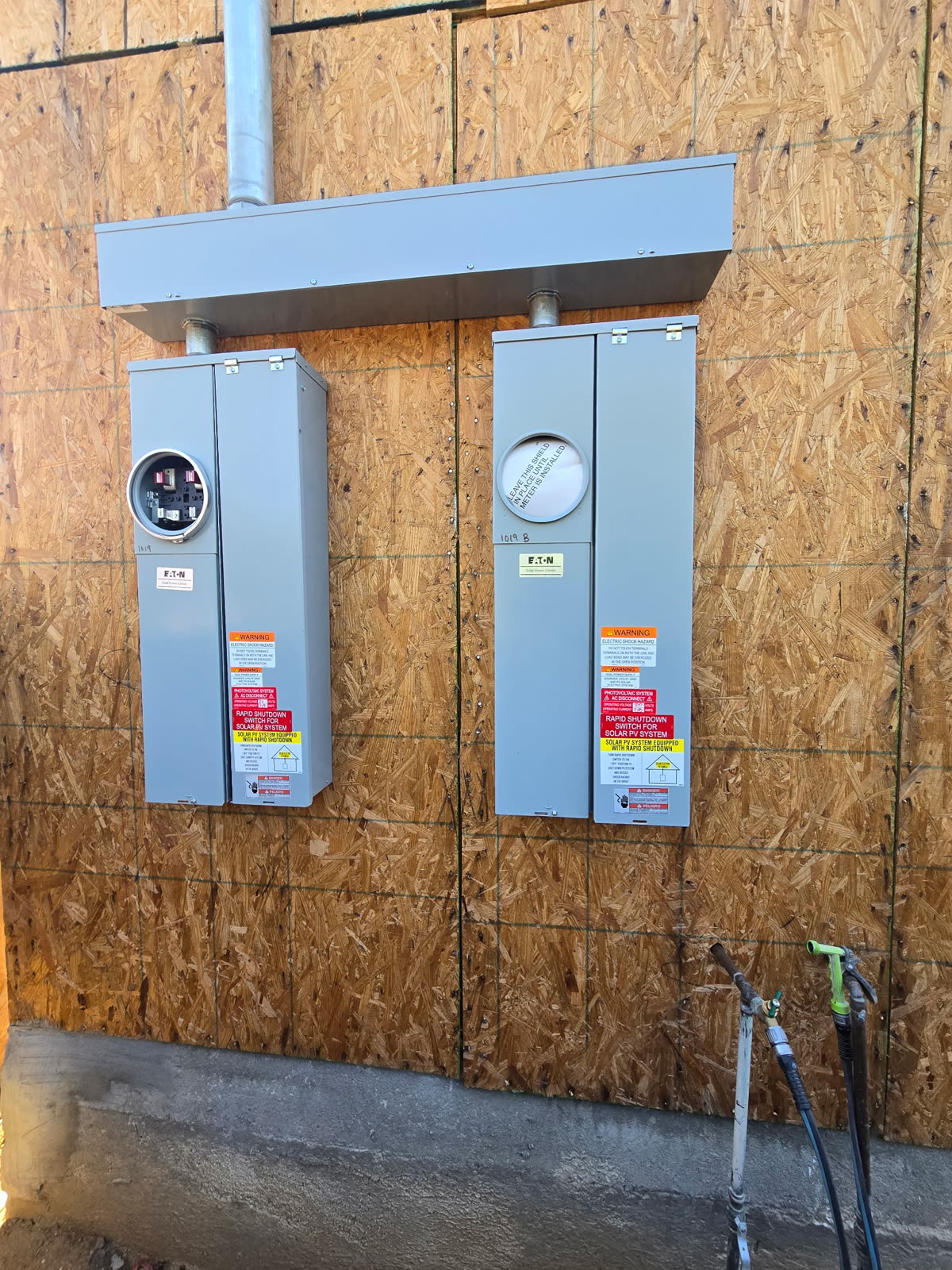 Pair of solar power centers and AC disconnects mounted and labeled on a sheathed equipment wall