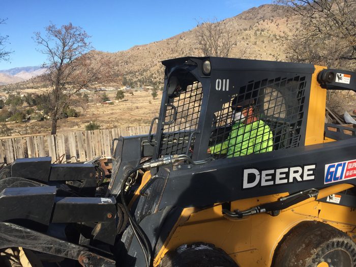 Skid steer clearing and grading an industrial site